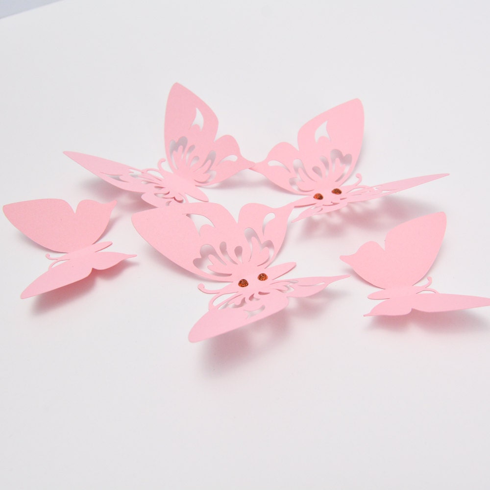 Arrangement of multiple pink paper butterflies of different sizes, creating an elegant and ethereal wall decoration for a child's nursery or bedroom.