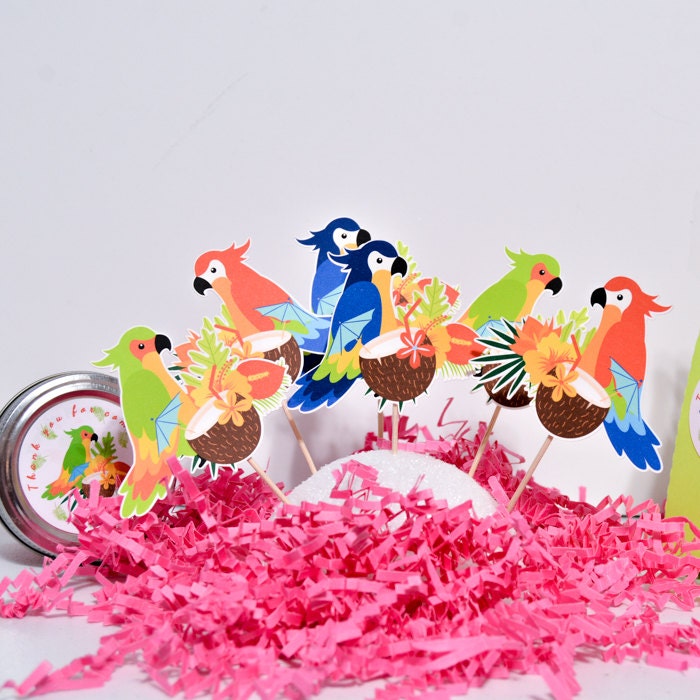Close-up row of tropical parrot cupcake toppers on sticks above bright pink paper filler.