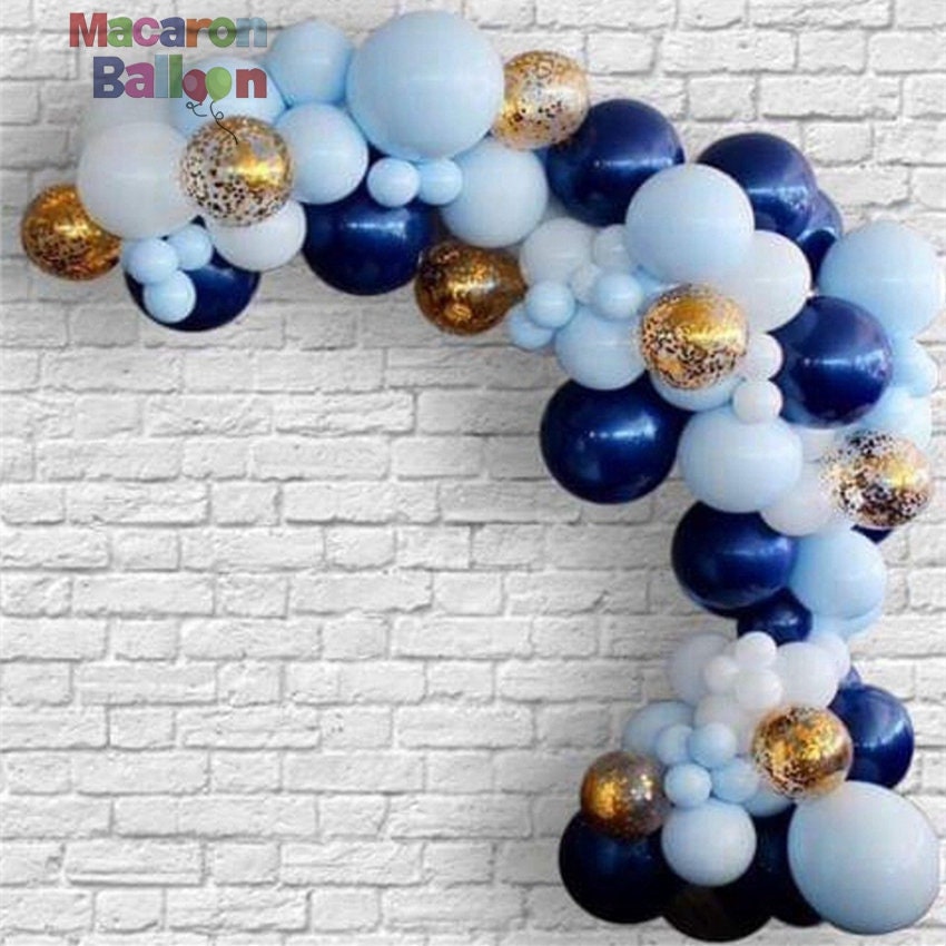 A festive navy, baby blue, and gold confetti balloon arch arranged at a birthday celebration with gifts in the foreground.