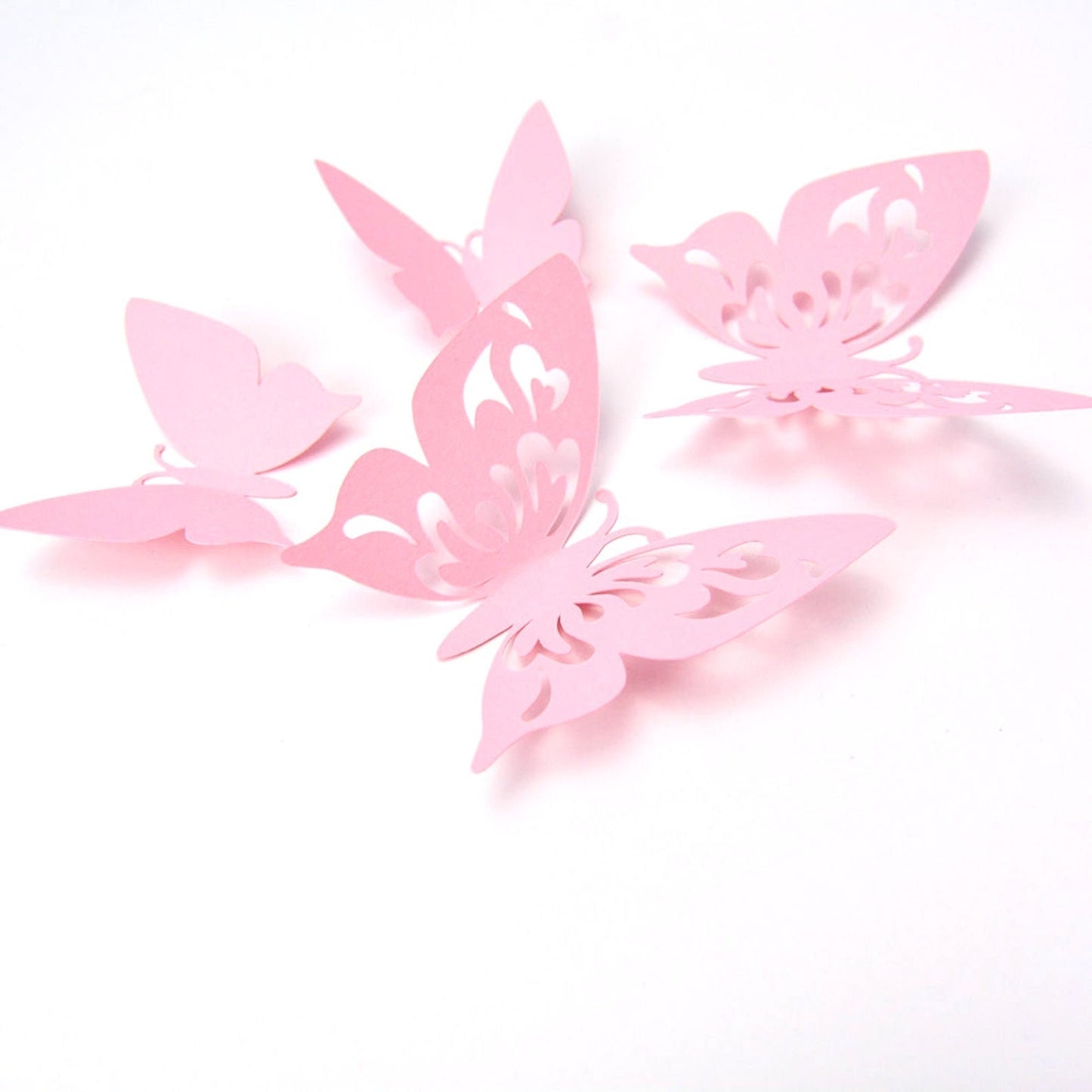 Assortment of pink paper butterflies with optional adhesive tabs, ready for party or nursery wall decoration setup.
