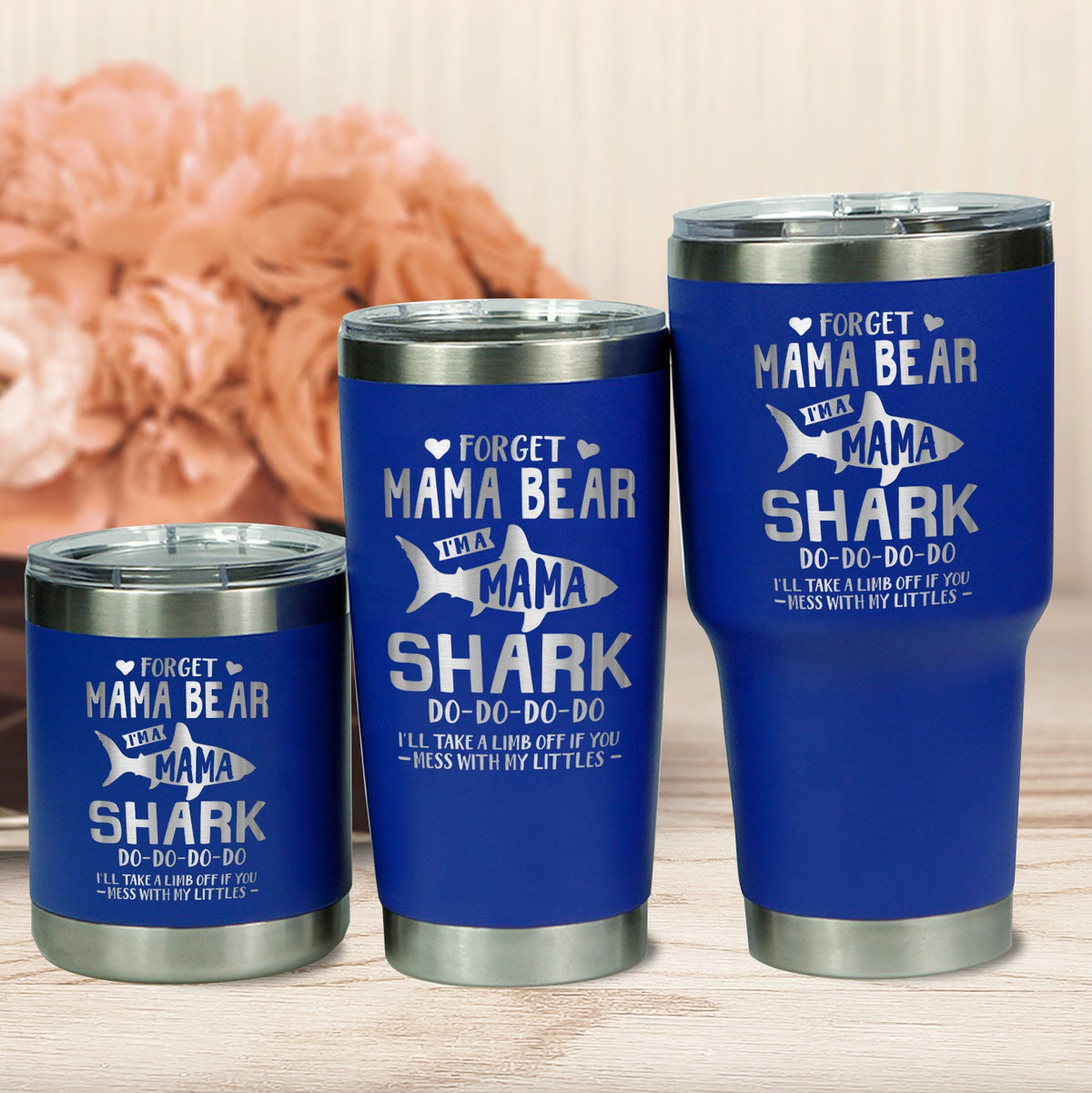 Three blue engraved Shark Mama cups arranged against a peach backdrop with dried flowers.