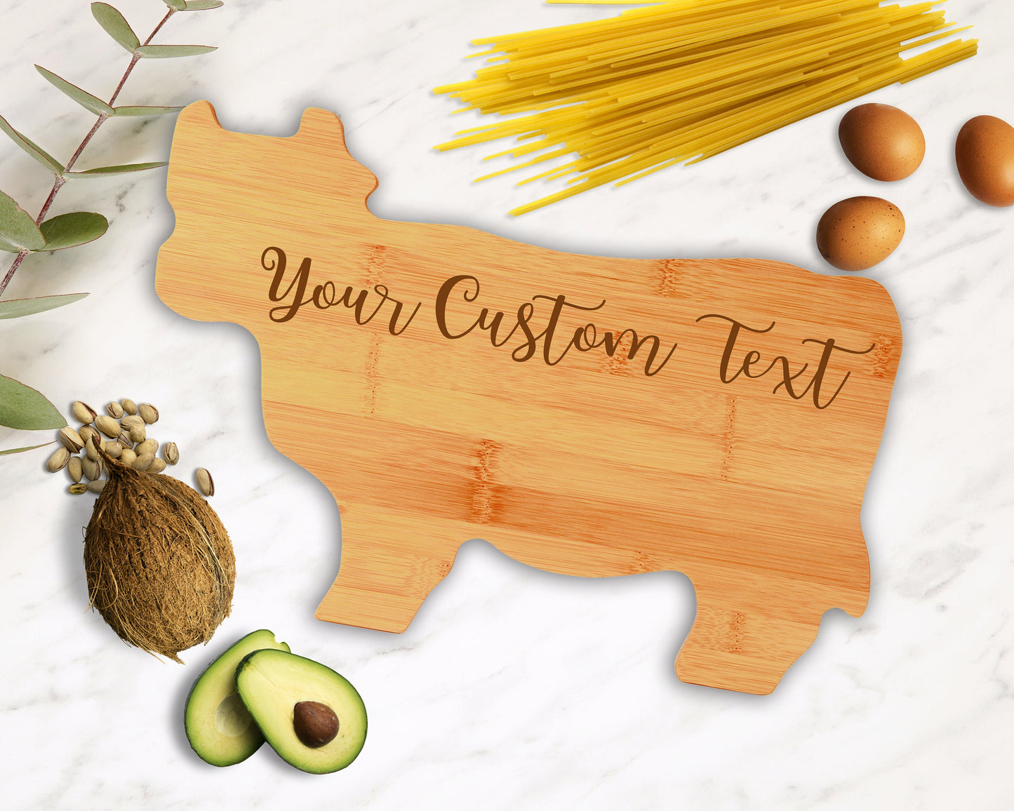Personalized cow-shaped bamboo cutting board with custom laser engraving, displayed on a rustic kitchen surface.