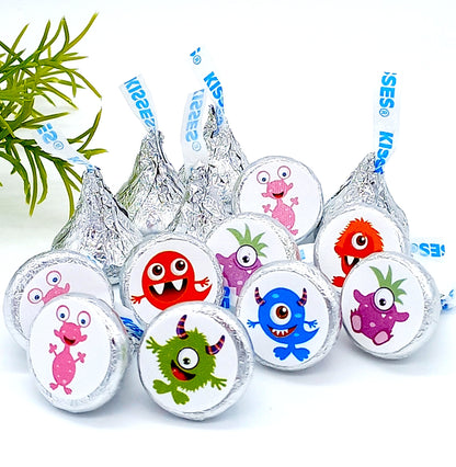 Little monster theme first birthday favors shown on a set of foil-wrapped chocolate kisses.
