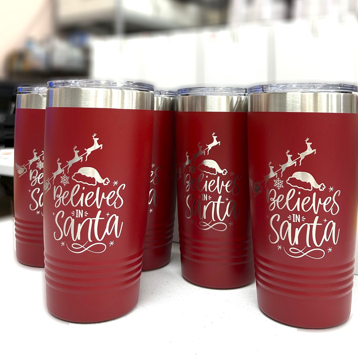 Close-up of 'Believes in Santa' laser-engraved text and charming reindeer design on a red Christmas tumbler.
