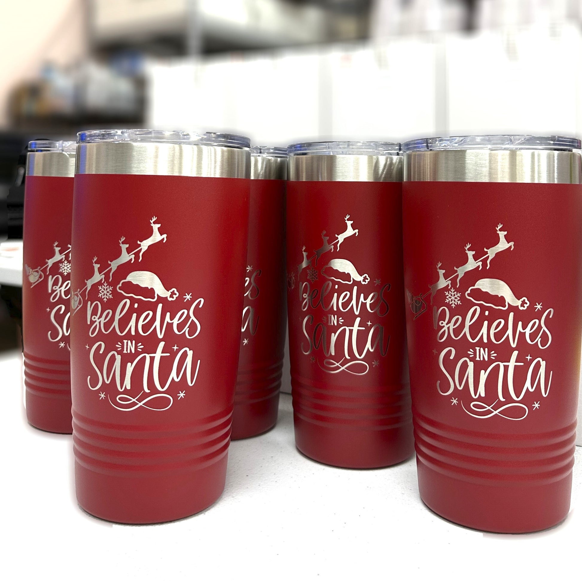 Close-up of 'Believes in Santa' laser-engraved text and charming reindeer design on a red Christmas tumbler.