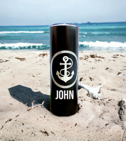 An anchor tumbler with custom laser engraving, shown in a natural setting, possibly on a boat or near water, for scale and context.