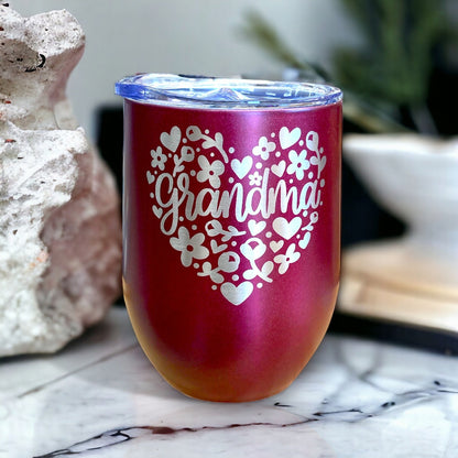 Pink stainless steel stemless mug featuring an engraved floral heart design, shown with its clear sip-through lid.