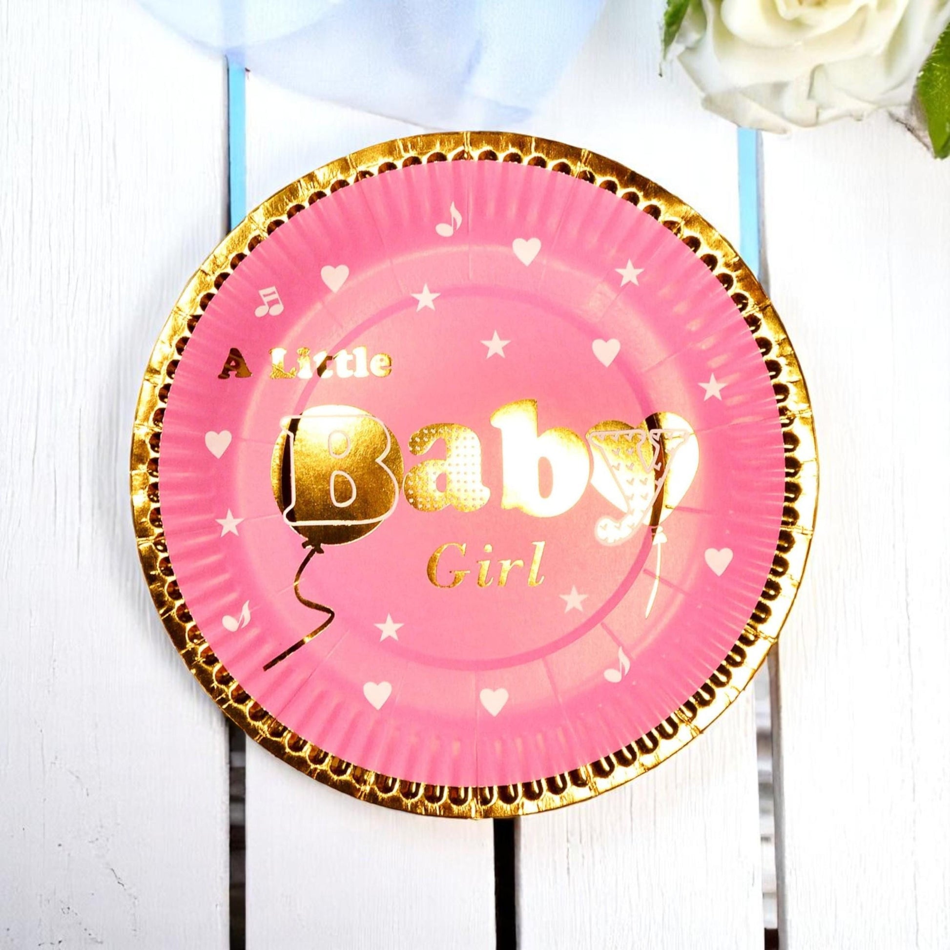 Arrangement of assorted gold foil baby shower plates in blue and pink, showcasing decorative details.