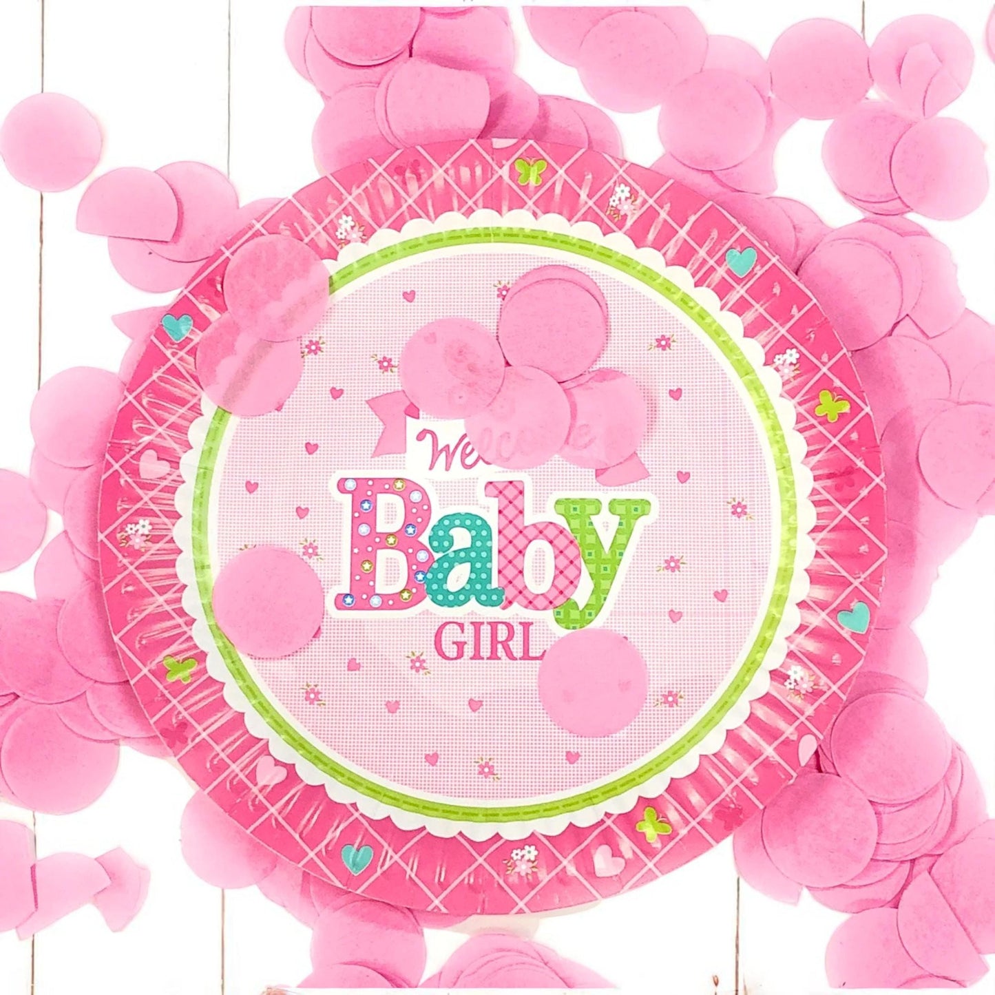 Two 'Welcome Baby Girl' dessert plates arranged with pink napkins and a small floral accent on a party table.