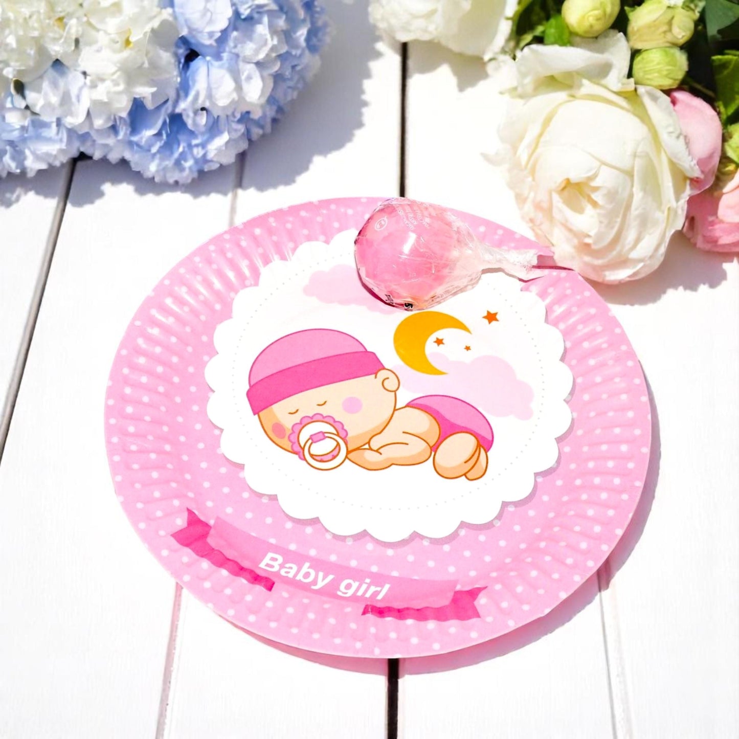 Angled view of a stack of pink sleeping baby girl dessert plates, showing the pretty floral border and sturdy paper material.