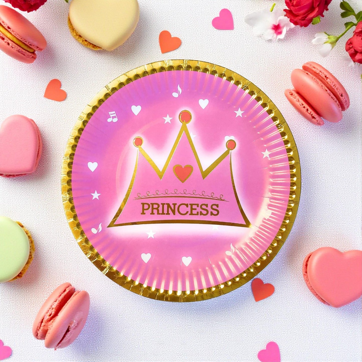 Stack of pink princess party paper dessert plates with gold crown design, ready for a celebration.
