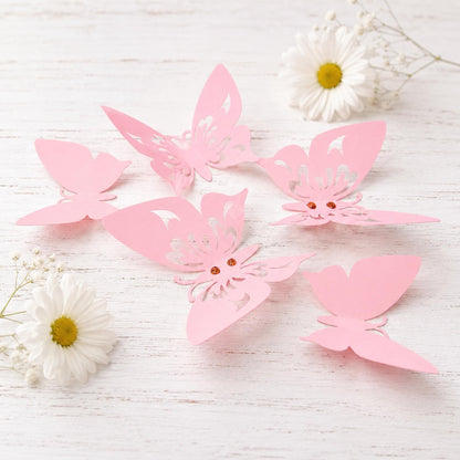 Collection of 12 pink 3D paper butterflies in varying sizes and shades, arranged artfully against a light-colored wall.