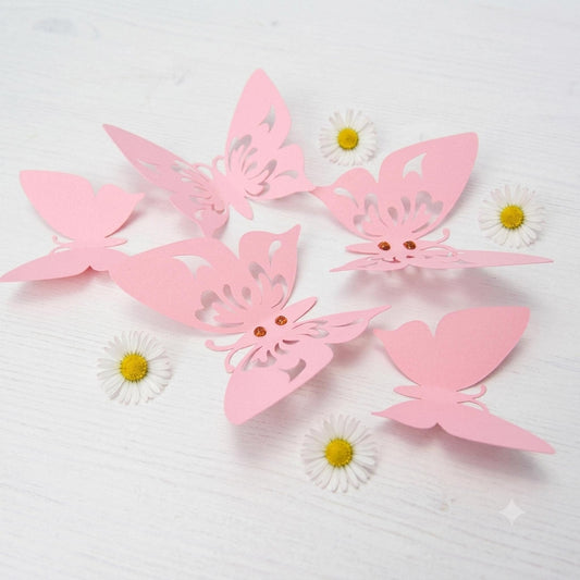 Close-up detail of a single pink 3D paper butterfly showing its layered wings, delicate folds, and subtle glitter accent on the body.