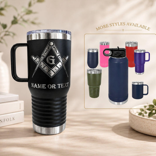 Freemason tumbler in stainless steel, shown in a natural setting on a dark wood desk with a book.