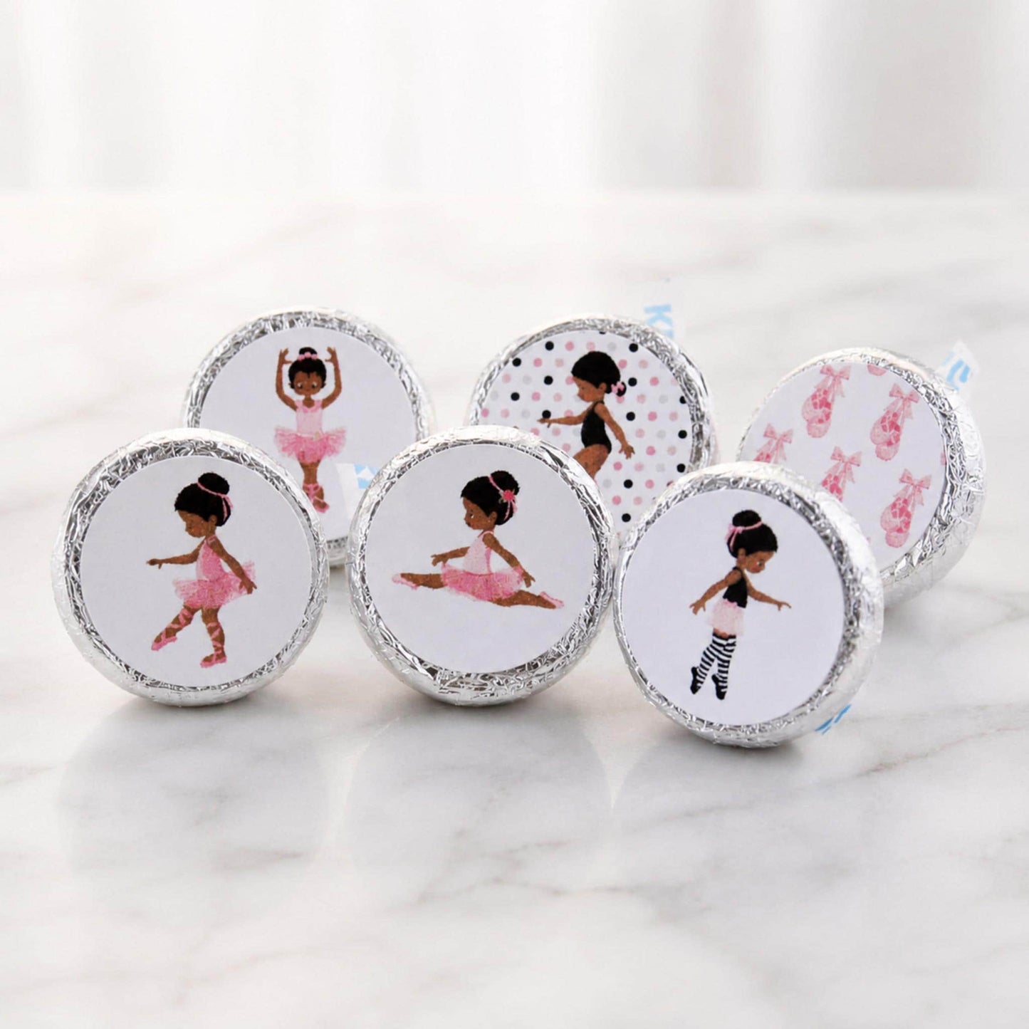 African American ballerina party favor labels displayed in a small basket on a festive dessert table.