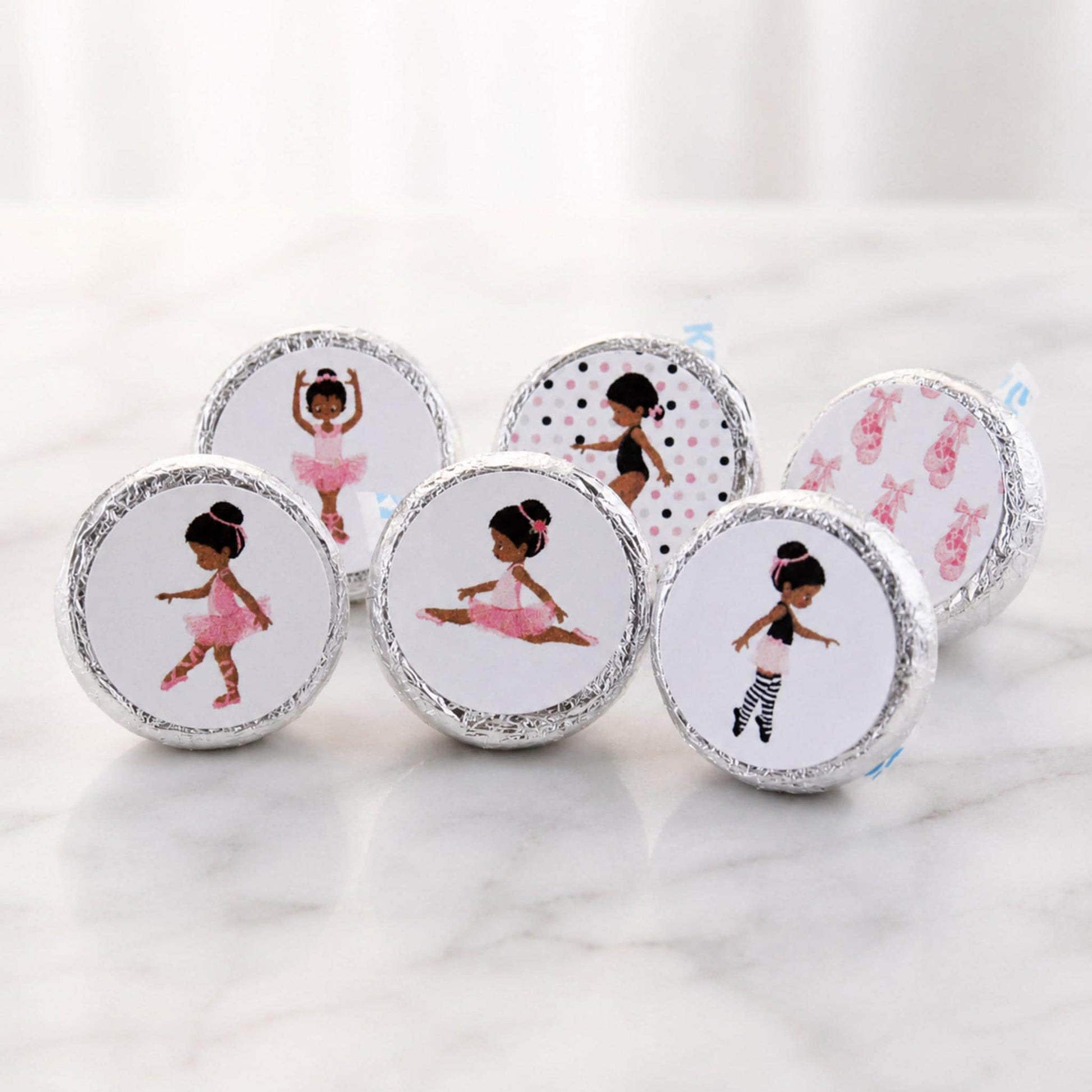 African American ballerina party favor labels displayed in a small basket on a festive dessert table.