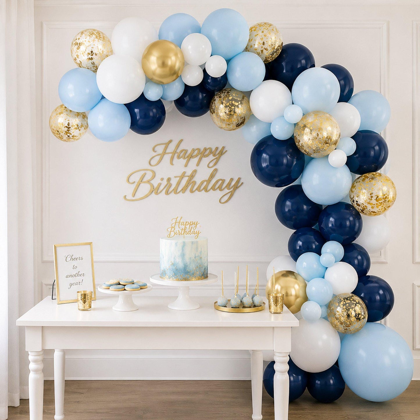 A vibrant blue and gold balloon arch kit styled as a party backdrop for a baby boy shower, with coordinating table decor.