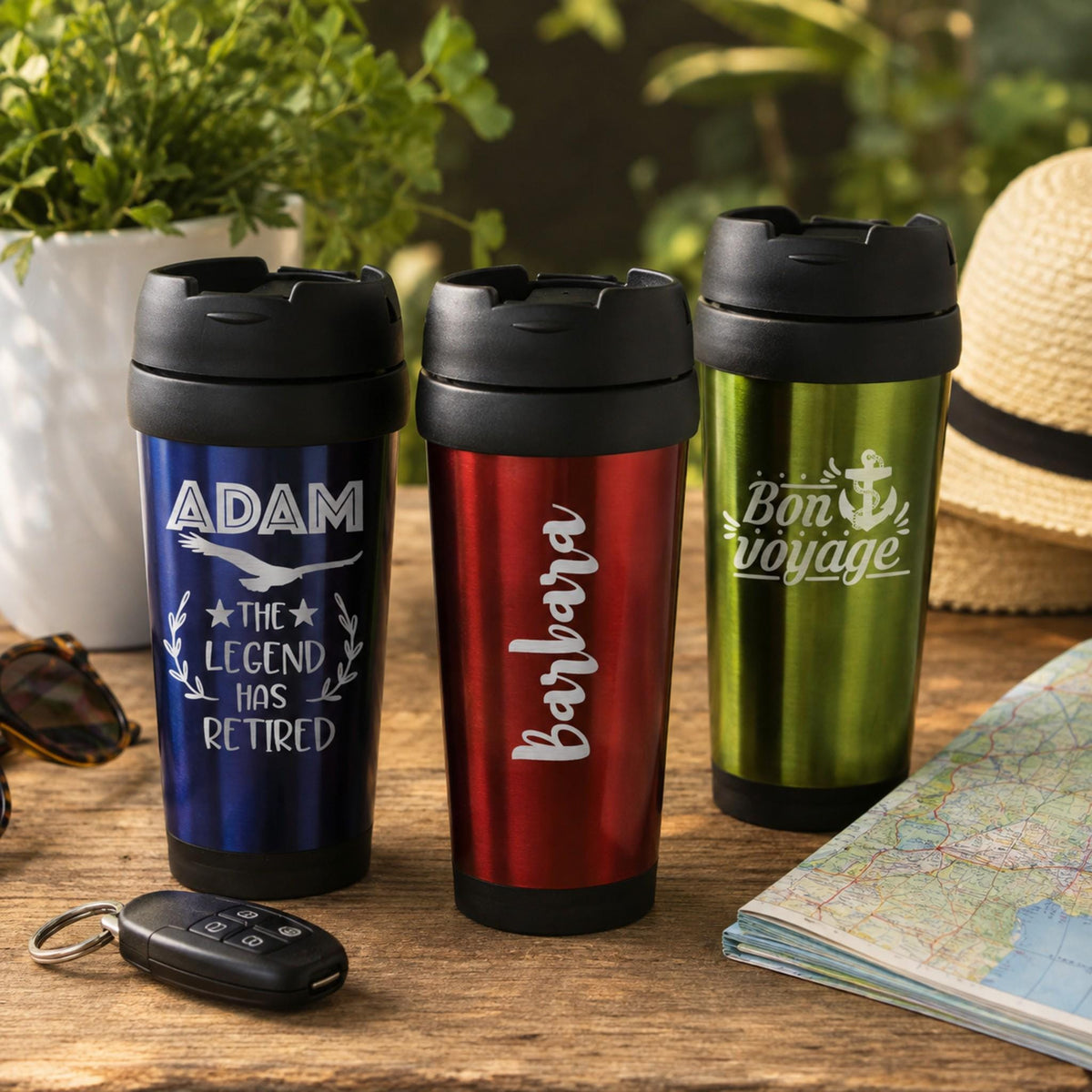 Engraved stainless steel travel mug in green, navy blue, and red with a screw-on lid.