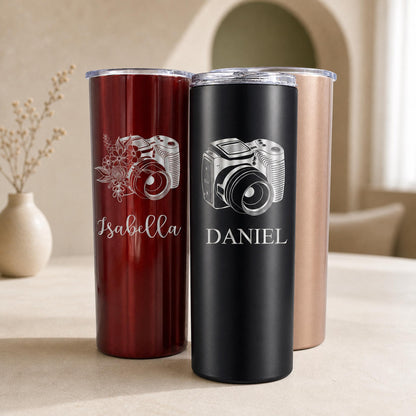 A white photographer tumbler cup with a laser-engraved camera lens design, 20 oz capacity, on a white background.