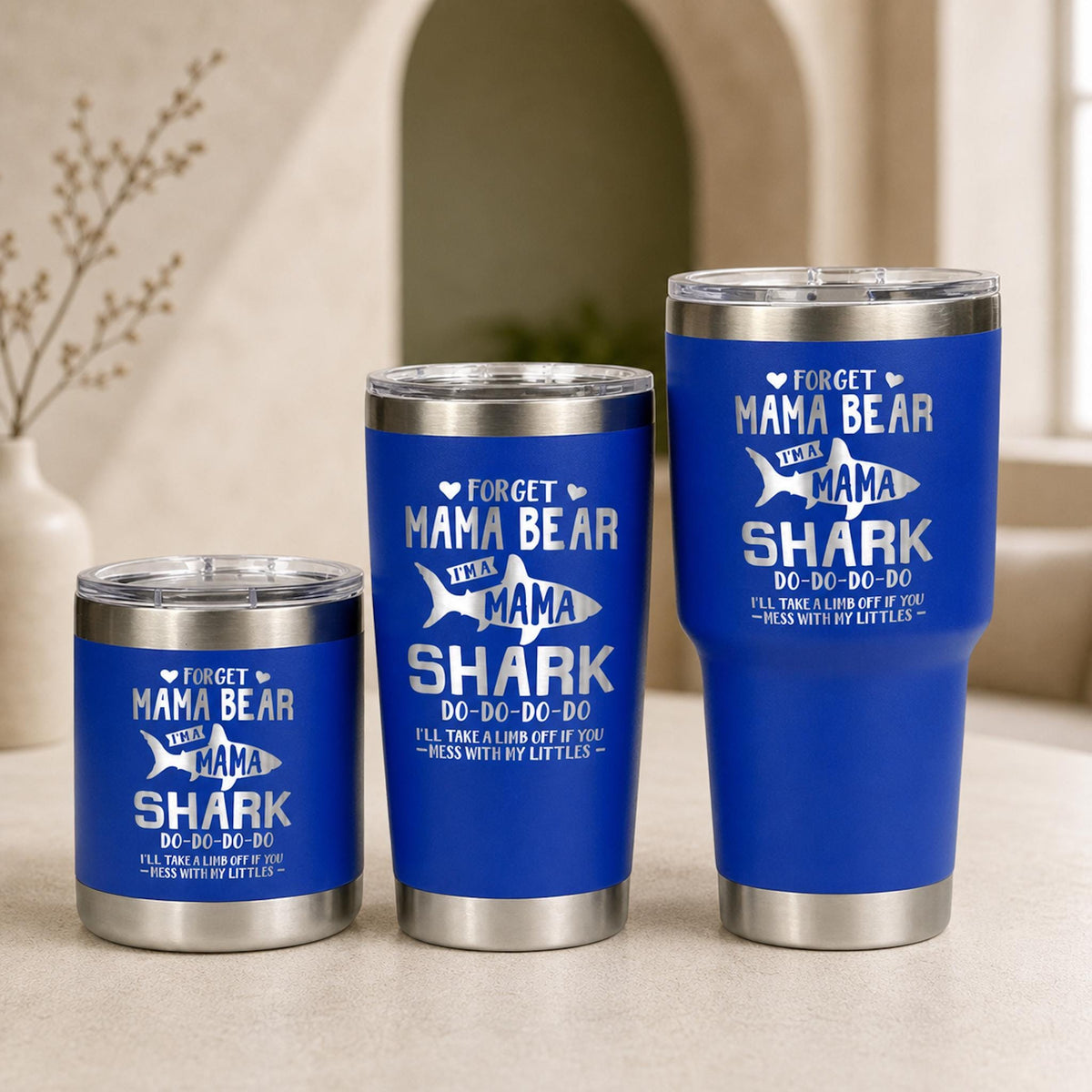 Three blue Shark Mama tumblers in 10 oz, 20 oz, and 30 oz sizes with silver engraved artwork.