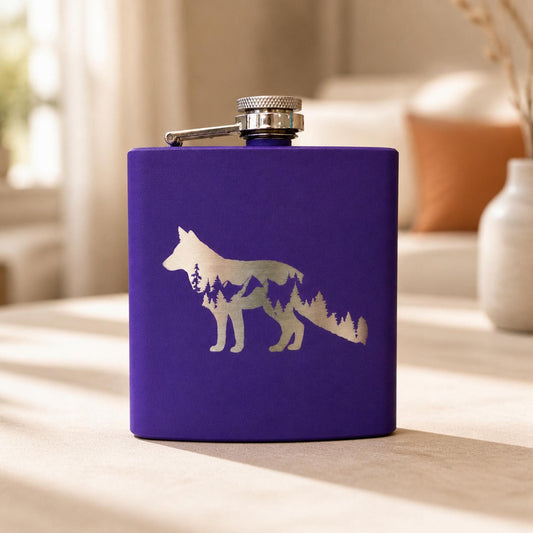 Purple engraved fox hip flask standing upright on a neutral tabletop with its attached silver cap visible.