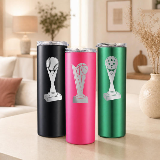 Three sports trophy tumblers in black, pink, and green displayed on a neutral tabletop.