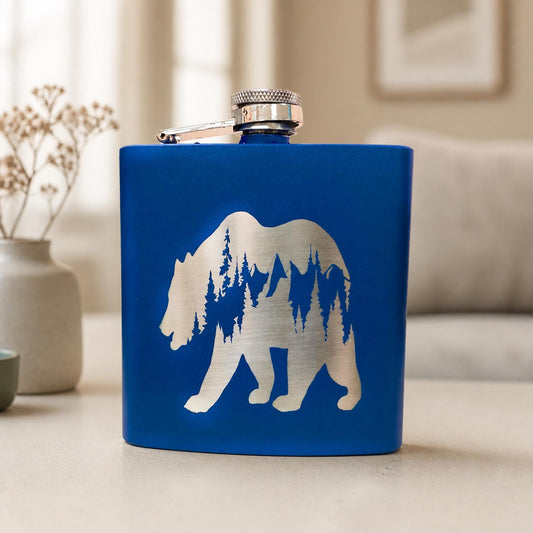 Blue personalized bear hip flask with a mountain forest silhouette and attached silver cap.