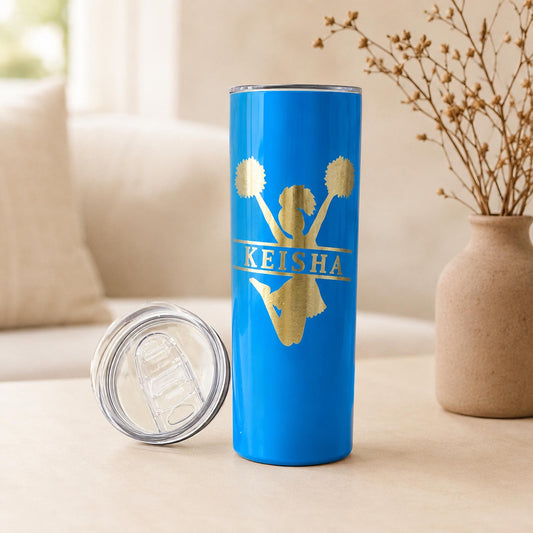 Bright blue personalized cheer tumbler with clear lid and gold-toned silhouette engraving.