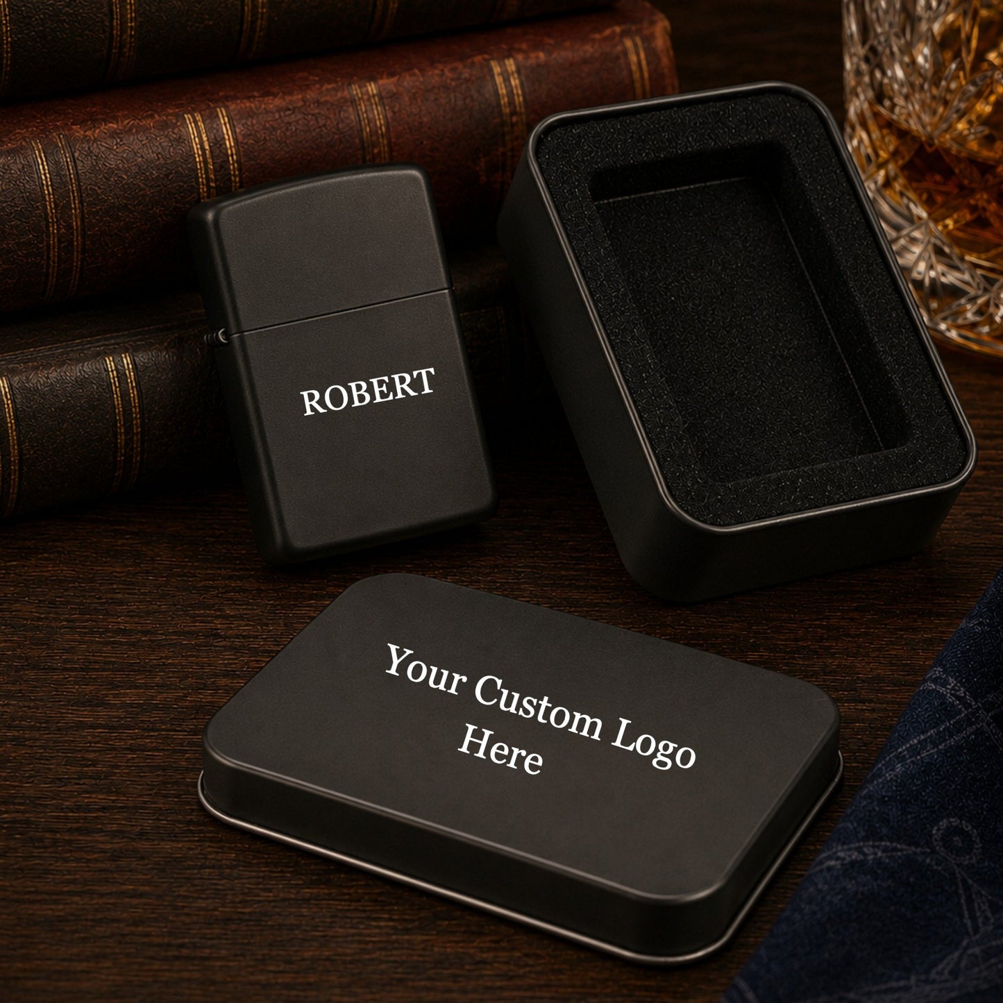 Matte black lighter and tin box, both custom engraved with different logos, on a clean surface.