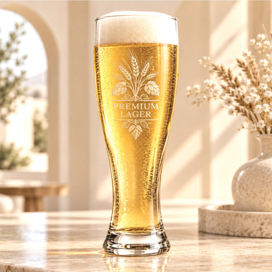 Custom laser engraved 16 oz pilsner beer glass with frosted wheat and hop crest logo and Premium Lager text, filled with golden beer